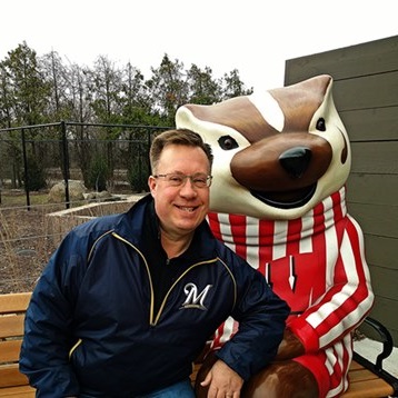 Mark Spahos sitting next to a statue of Bucky Badger